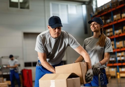 warehouse-worker-assisting-female-colleague-with-packages-industrial-storage-compartment_11zon